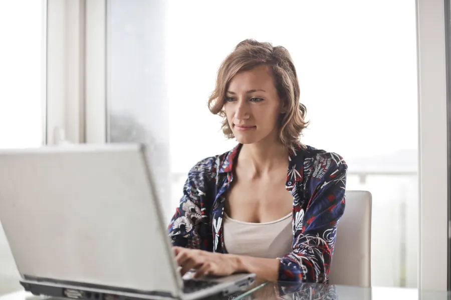 Una persona trabajando en un escritorio luminoso, con el móvil como algo secundario.