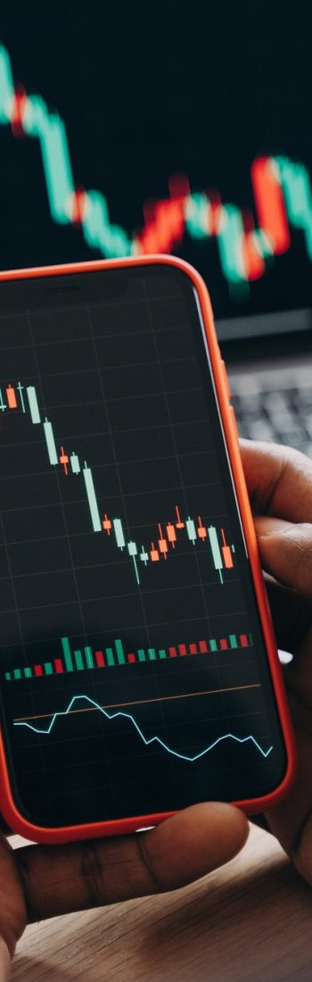 African man stock trader holding smartphone with financial charts and trading online investment data